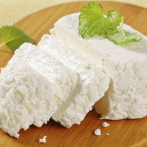 sliced ricotta cheese with a fresh mint on a wooden cutting board